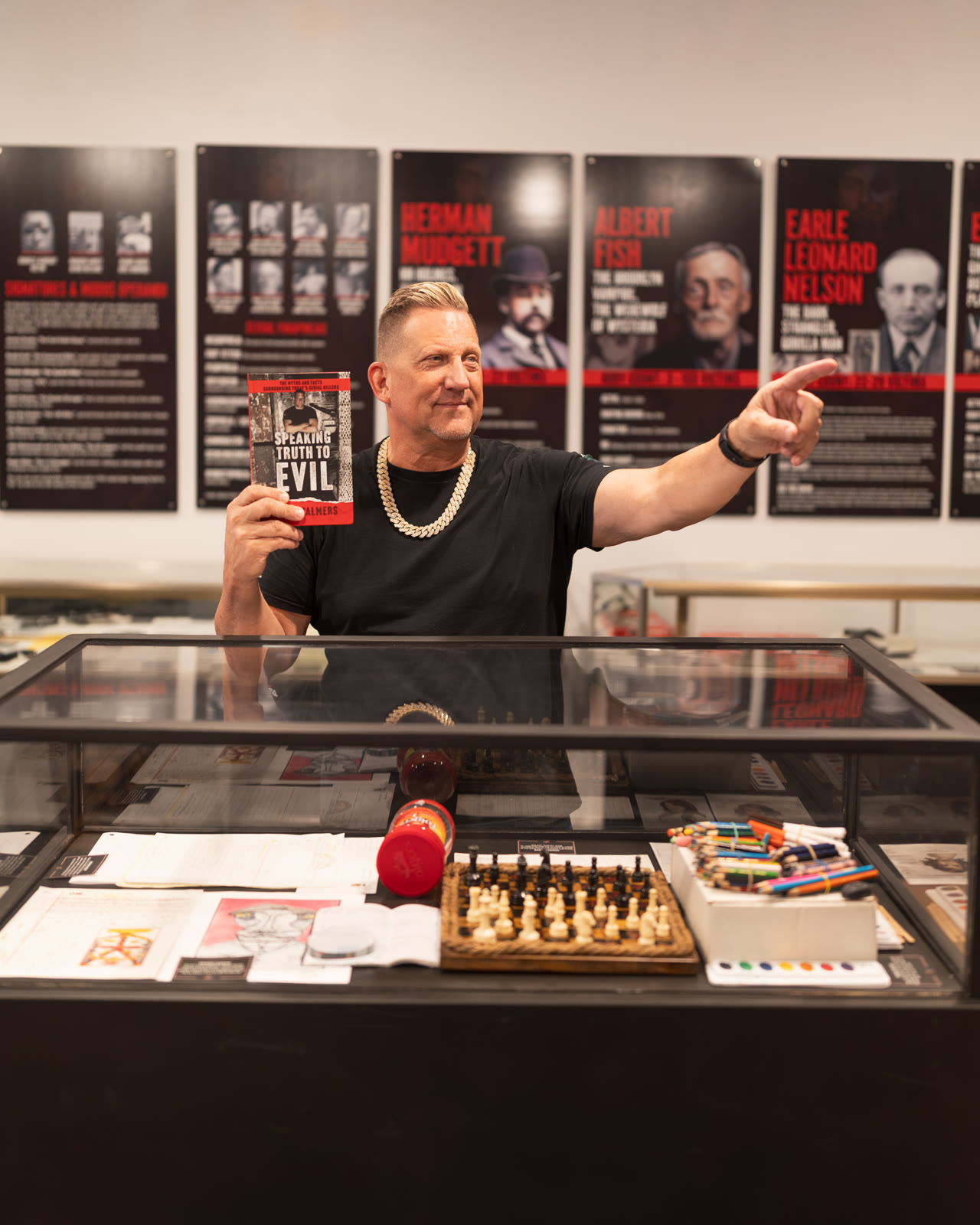 Phil Chalmers holding his book Speaking Truth To Evil in the museum