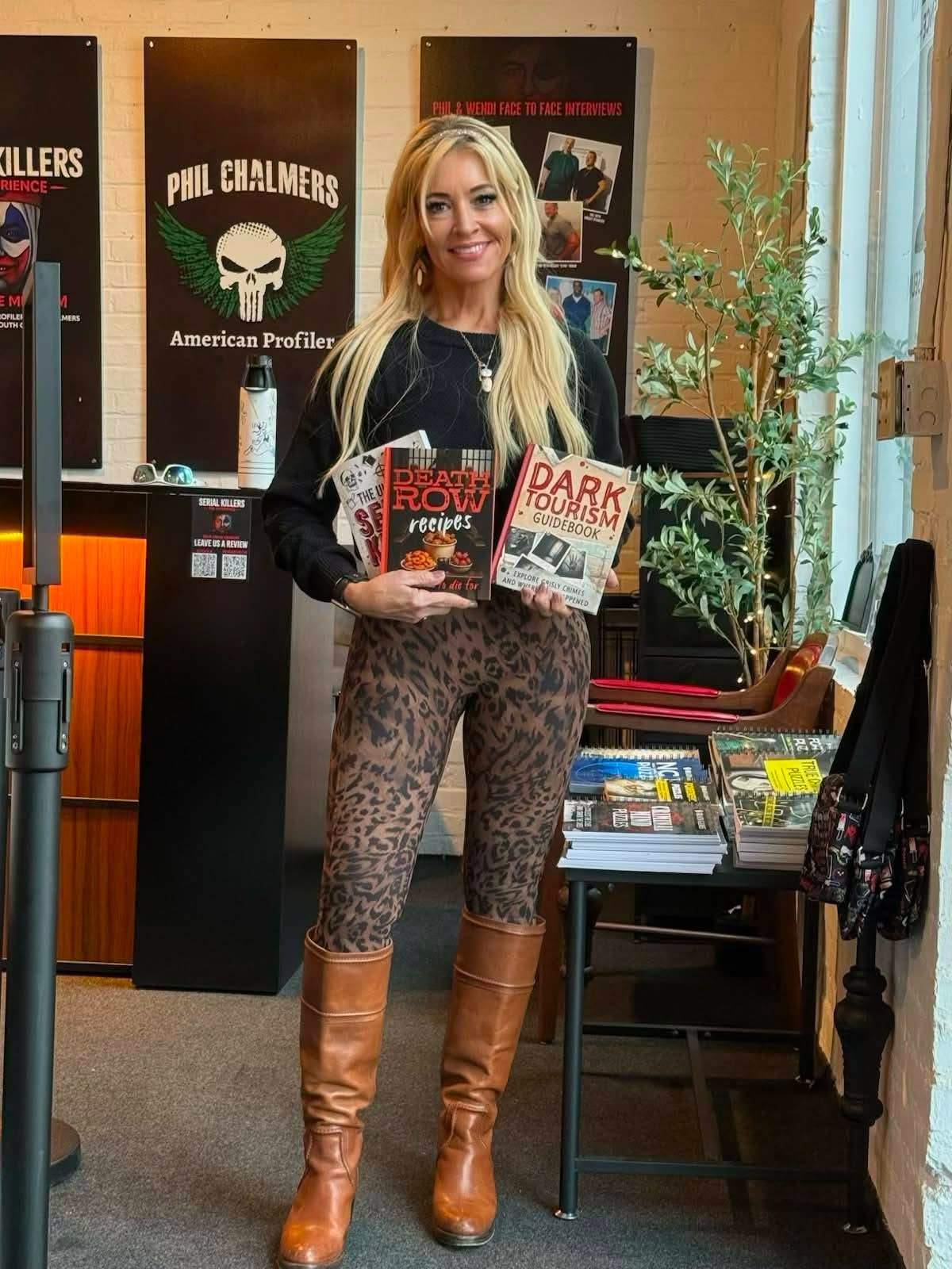 Wendi Chalmers holding Phil Chalmers' true-crime books at the museum